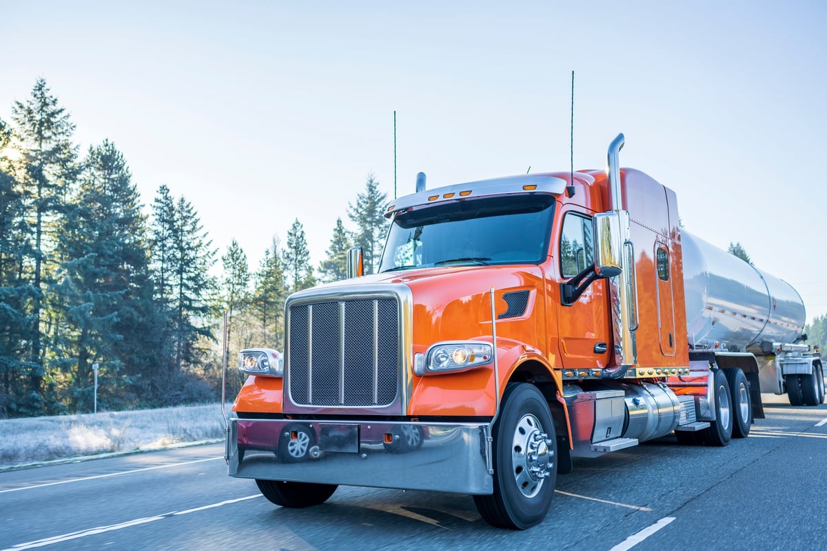 A big rig hauling a tank trailer on a frosty winter road