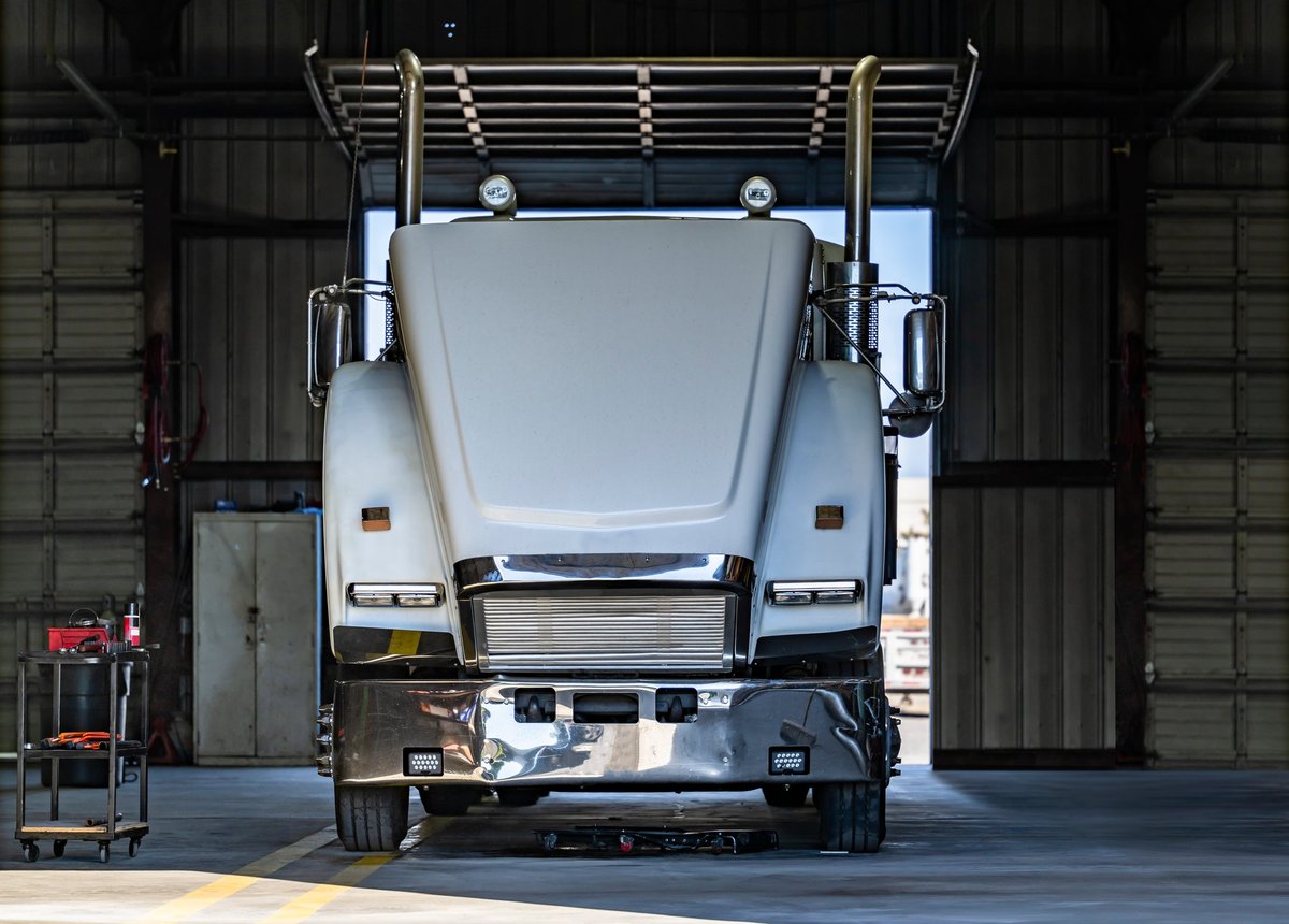 A big rig semi truck with its hood open in a workshop