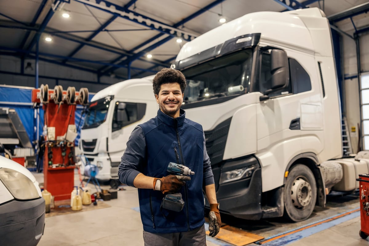 A technician standing with service trucks in the background