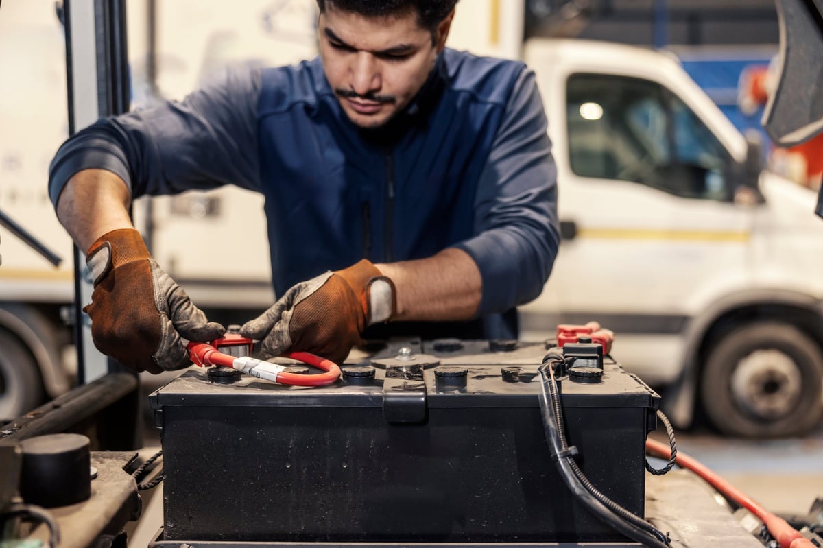 Hands using a battery charger at a mechanic shop