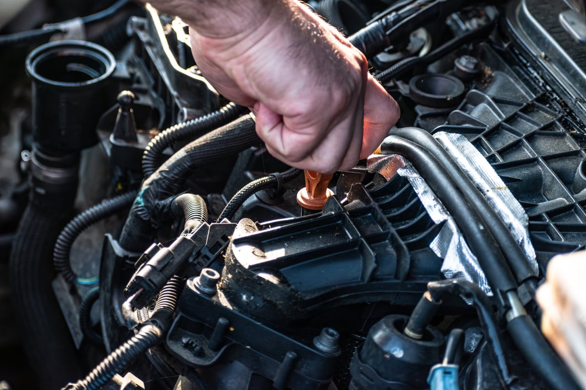 A mechanic checking the oil level on a diesel engine
