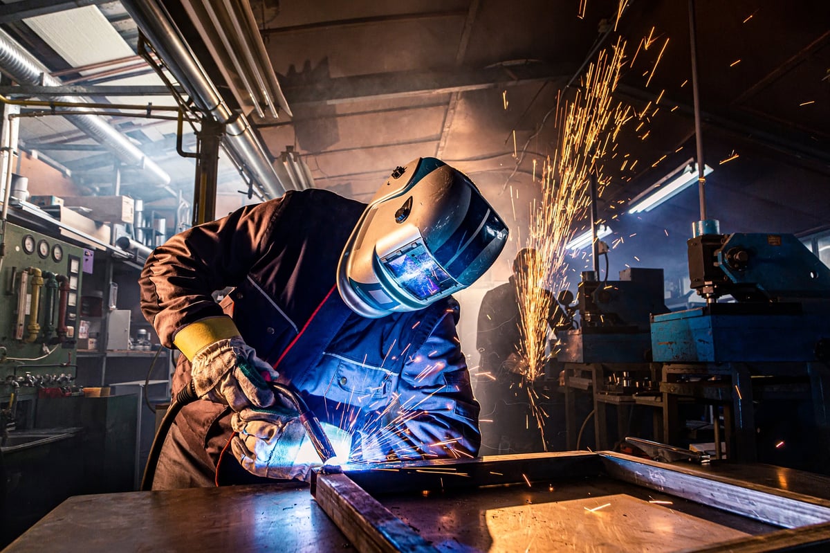 A welder striking bright sparks during fabrication