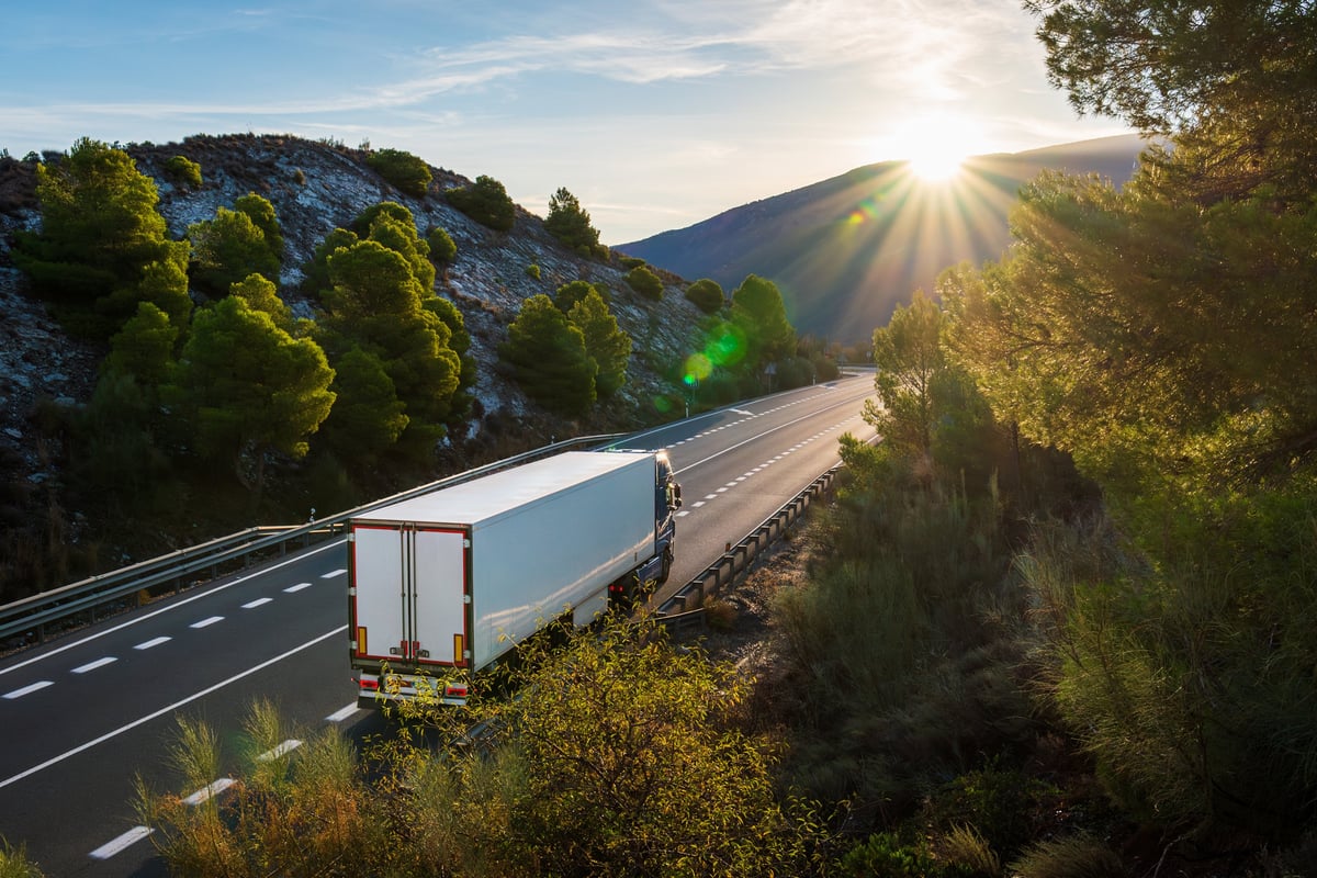 A refrigerated semi truck cruising through mountain scenery