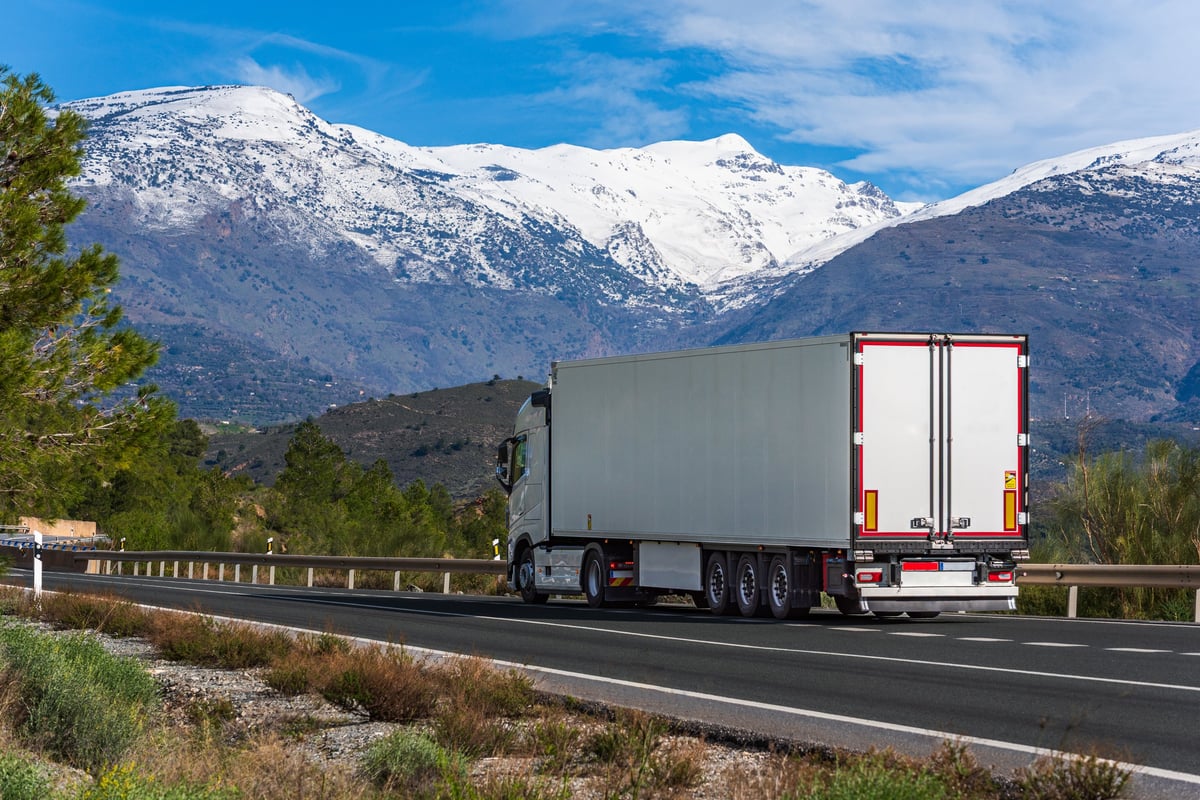 A semi truck rolling through winter mountain scenery