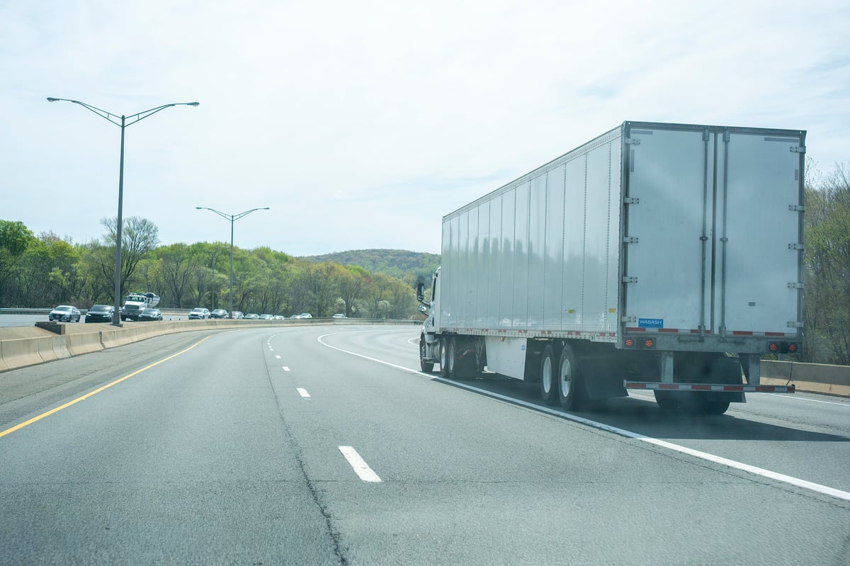 A white semi truck on an open highway at golden hour
