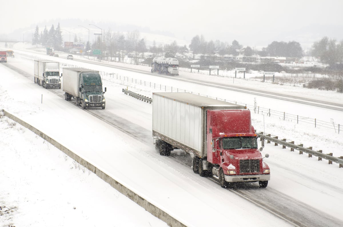 A semi truck in traffic during a winter snow and freezing rain storm